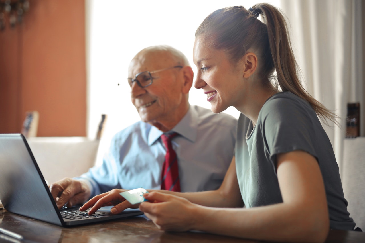 A woman helping an elderly use a laptop