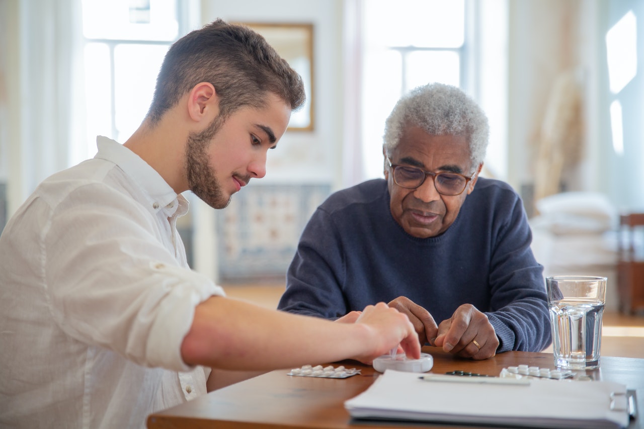 A young man giving an elderly meds